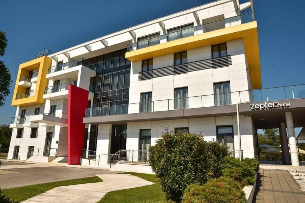 un edificio blanco y amarillo con un techo rojo en Zepter Hotel, en Bosanska Dubica