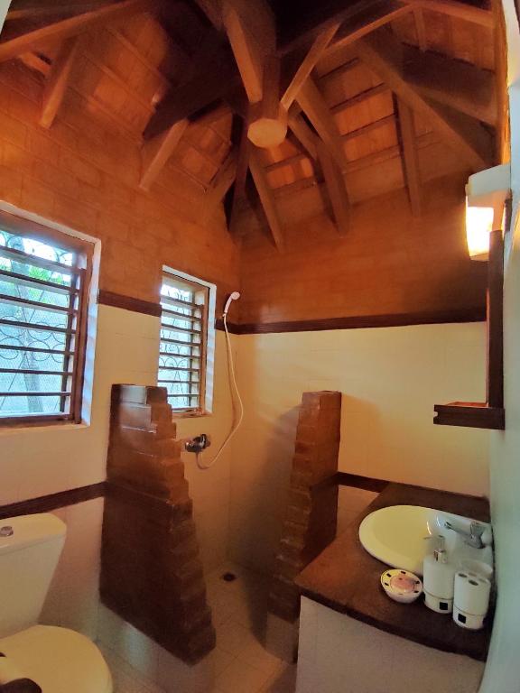 bagno con servizi igienici e soffitto in legno di Hotel Benjamin ad Ambatoloaka