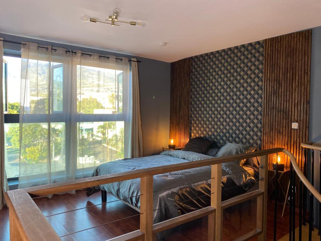 a bedroom with a bed and a large window at LOFT DIONYSIEN DE STANDING in Saint-Denis