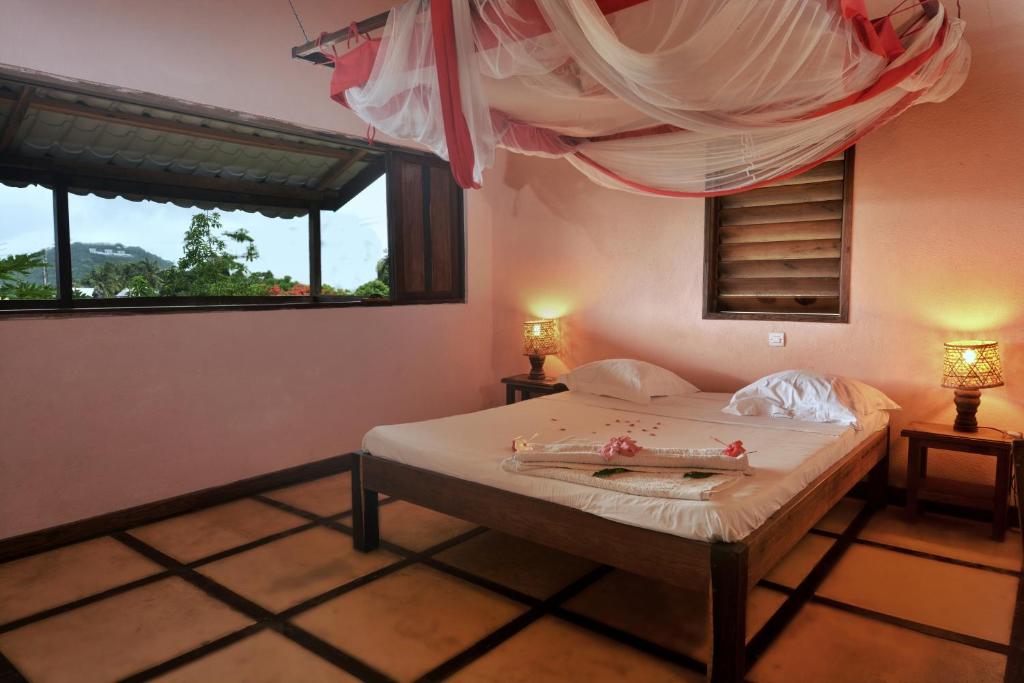 a bedroom with a bed with two lamps and a window at Hotel Benjamin in Ambatoloaka