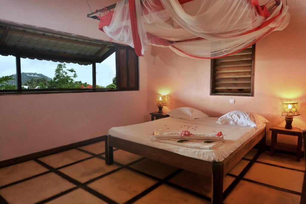 una camera da letto con un letto con due lampade e una finestra di Hotel Benjamin ad Ambatoloaka