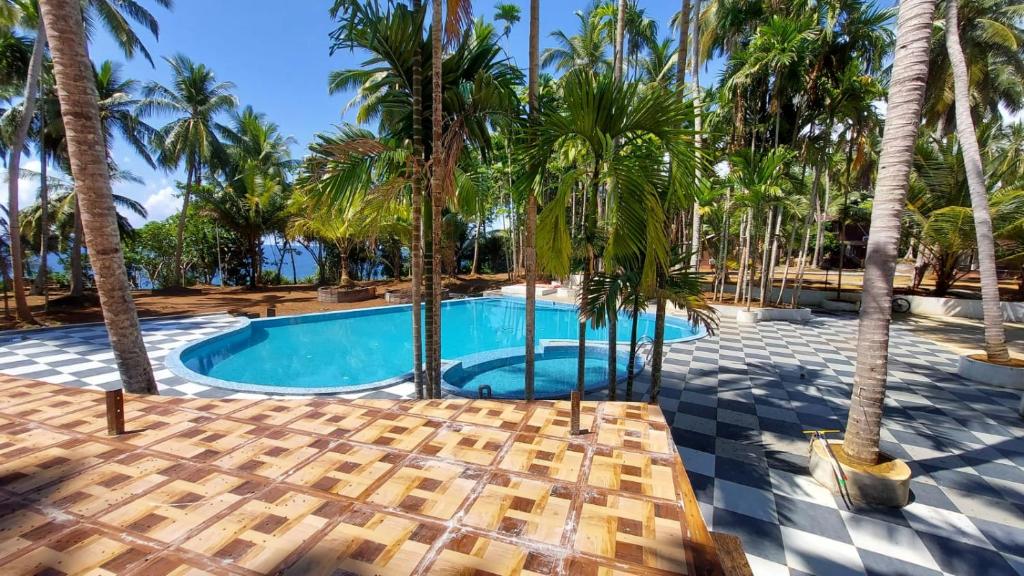 a swimming pool with palm trees and a resort at Adhvasaha Beach Spa Resort in Port Blair