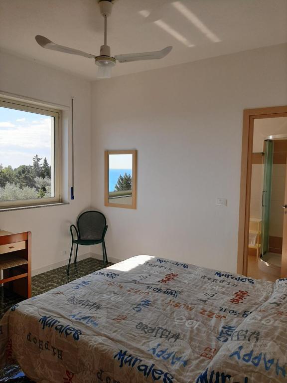 a bedroom with a bed and a chair and a window at Hotel Conca d'Oro in Stalettì