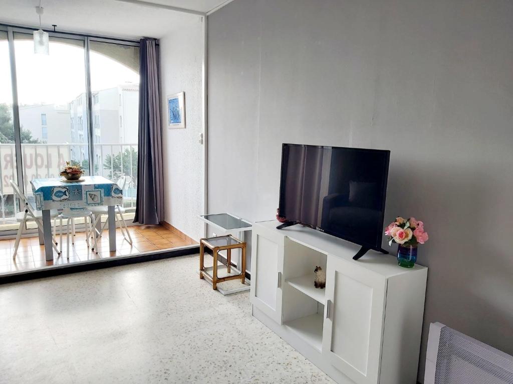 a living room with a flat screen tv on a white cabinet at Studio Cap d'Agde le Môle in Cap d'Agde