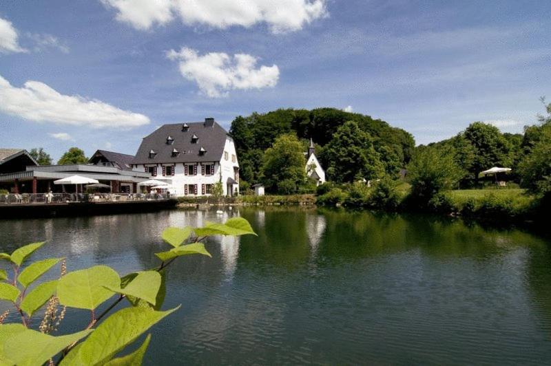 a large house sitting on the side of a river at Malteser Komturei Hotel / Restaurant in Bergisch Gladbach
