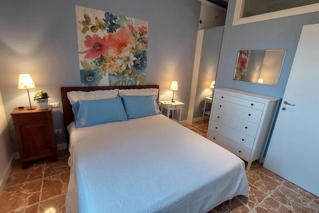 una camera da letto con un grande letto bianco con cuscini blu di Appartamento - Lì de Là tra i fiori a Villafranca di Verona