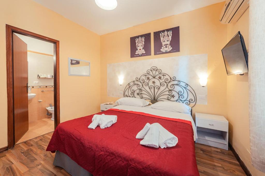 a bedroom with a red bed with towels on it at Taormina Garden Hotel in Taormina