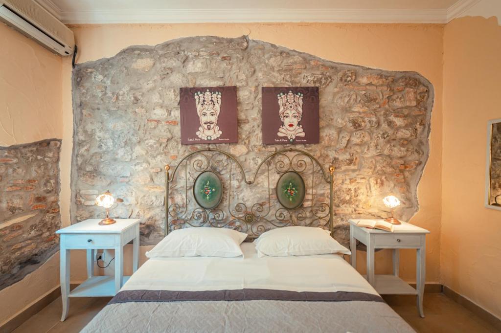a bedroom with a stone wall with a bed and two tables at Taormina Garden Hotel in Taormina