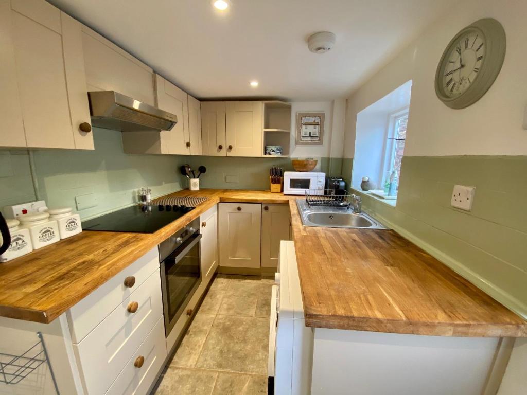 a kitchen with white cabinets and a clock on the wall at Cloud Nine in Otterton