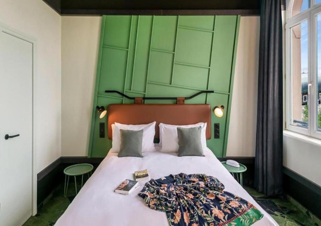 a bedroom with a bed with a green headboard at Hôtel Tandem - Boutique Hôtel in Strasbourg