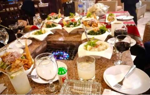 a table with plates of food and glasses of wine at Saint John Hotel in Madaba