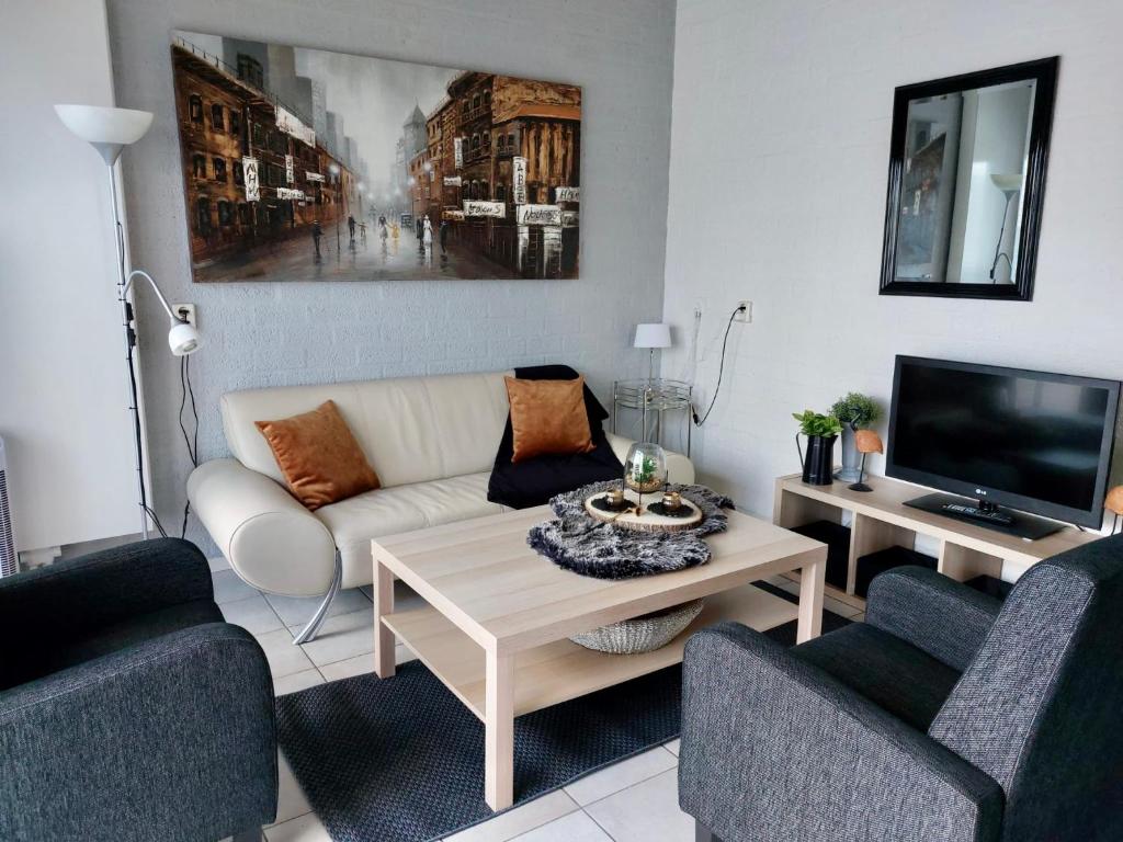 ein Wohnzimmer mit einem weißen Sofa und einem TV in der Unterkunft Casa della nonna bungalow 2 in Simpelveld