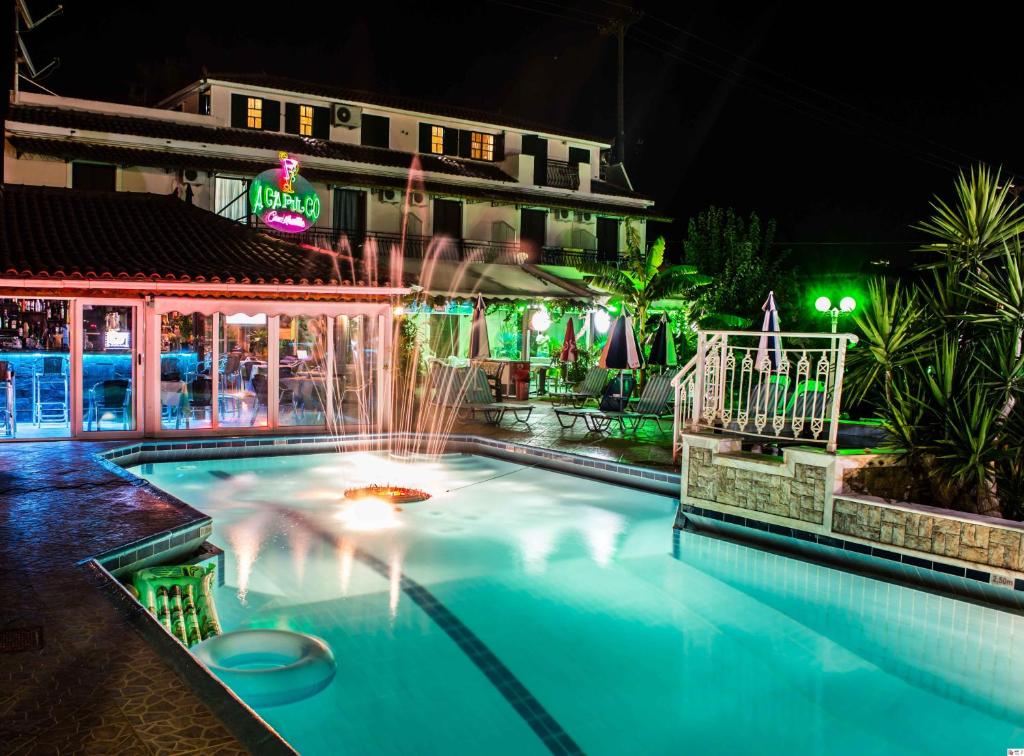 a swimming pool with a fountain in front of a building at Acapulco Marinos Apartments- Adults Only in Laganas