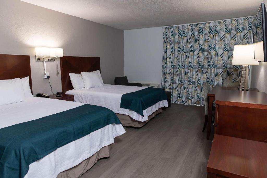 a hotel room with two beds and a desk at Studio 6 Ocala, FL in Ocala