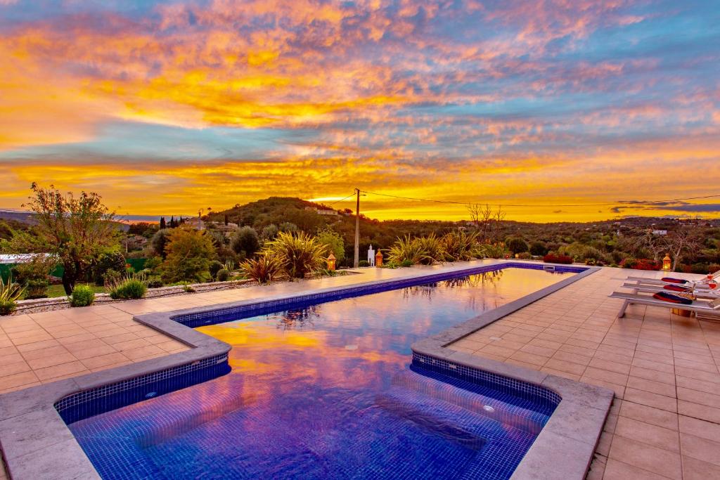 una piscina con puesta de sol en el fondo en Good Life Villa with Private Pool & Fruit garden, en Loulé