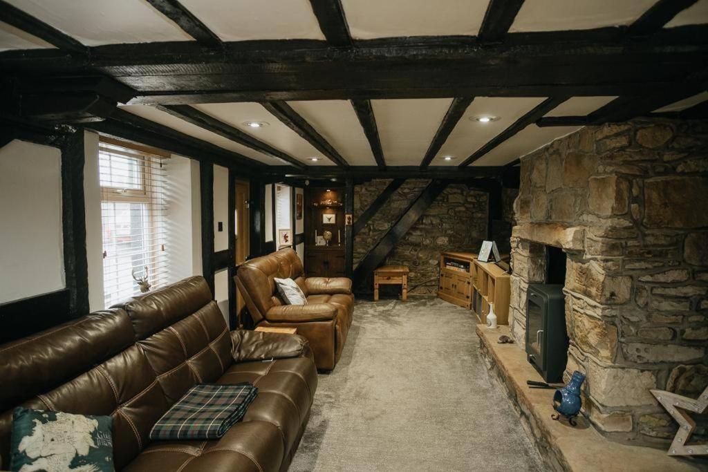 a living room with a couch and a stone fireplace at WILSONS COTTAGE - 2 Bed Classic Cottage located in Cumbria with a cosy fire in Camerton