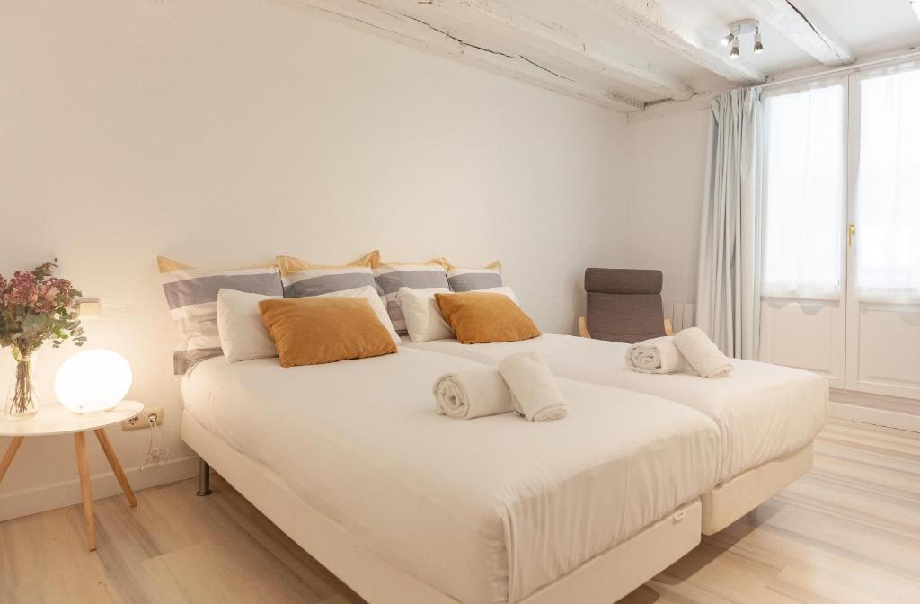 a white bedroom with a large white bed with pillows at Boulevard 26 in San Sebastián