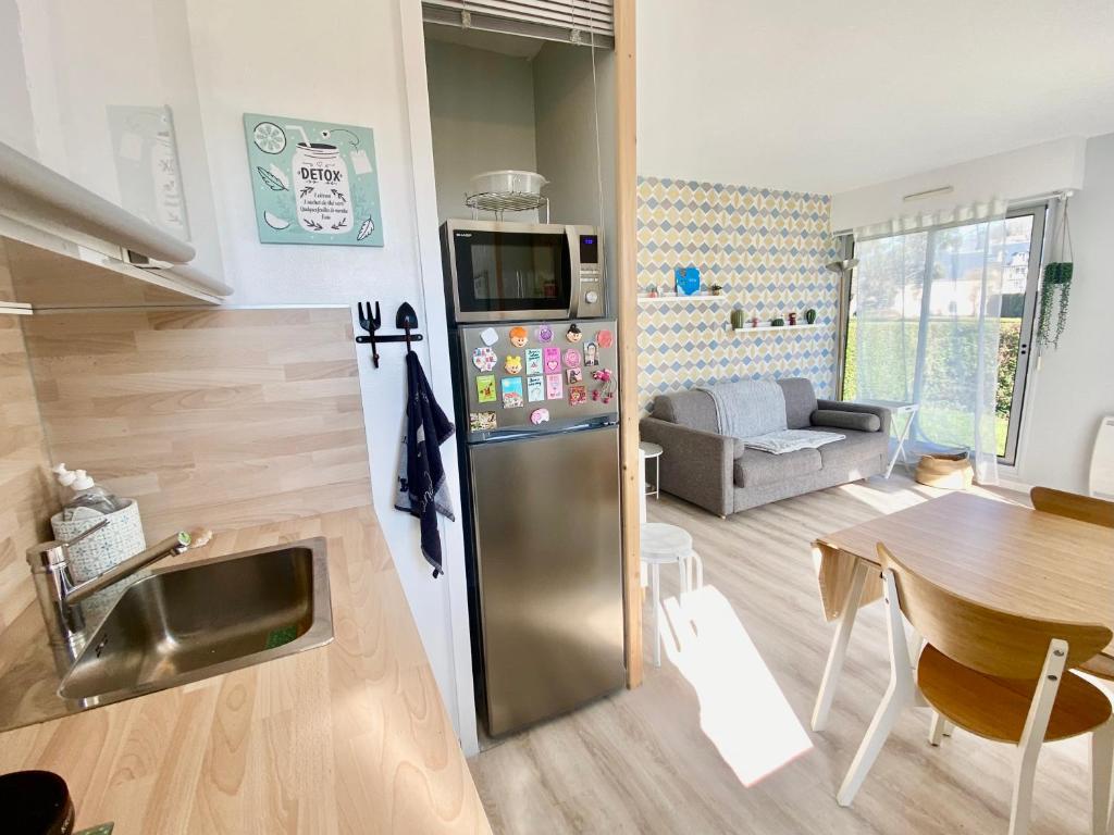 uma cozinha com um frigorífico de aço inoxidável e uma mesa em Superbe appartement avec jardin ensoleillé em Blonville-sur-Mer