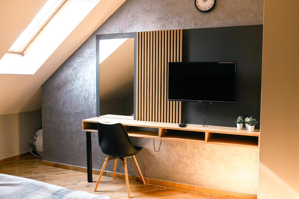 a bedroom with a desk with a television on a wall at Manoir Apartments City Center in Novi Sad
