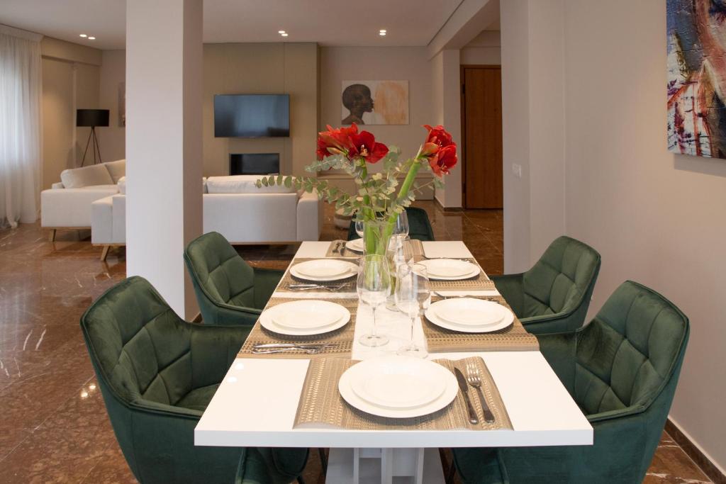 tavolo da pranzo con sedie verdi e vaso di fiori di Athenais Luxury Apartment ad Atene