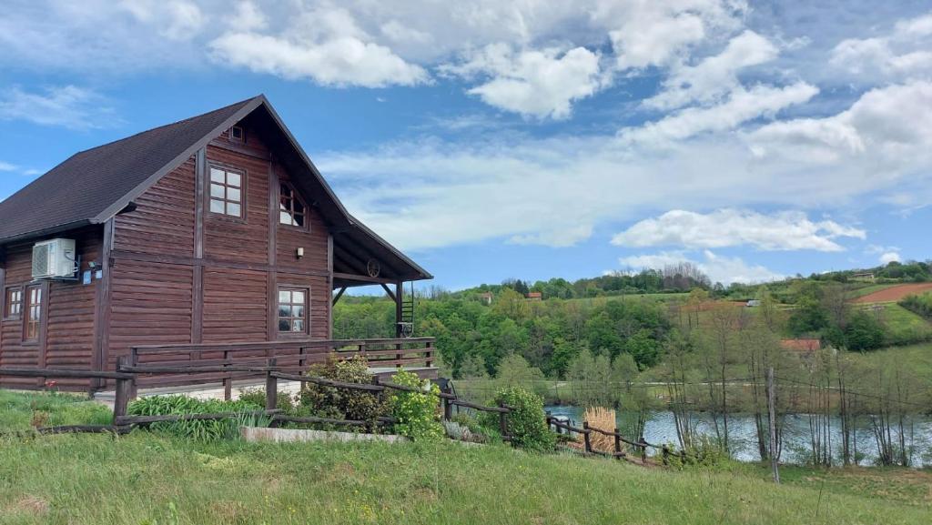 a large wooden house in a field next to a river at House for rent Mrežnica in Duga Resa