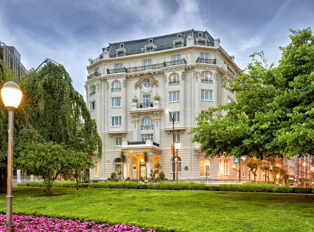 un grand bâtiment blanc avec une pelouse devant lui dans l'établissement Hotel Carlton, à Bilbao