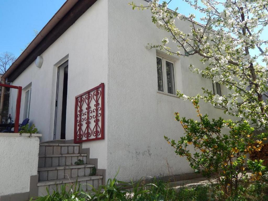 a white house with a red sign on the side of it at Apartman Megy in Senj