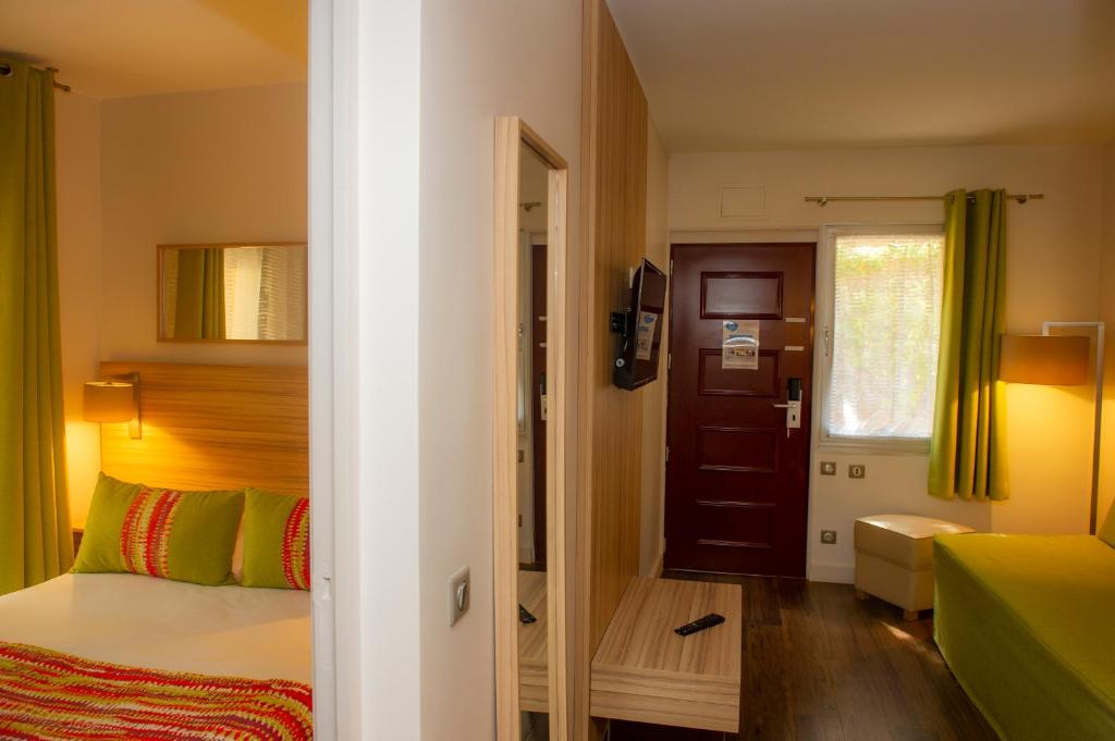 a bedroom with a bed and a door to a room at Hôtel Vacances Bleues Delcloy in Saint-Jean-Cap-Ferrat