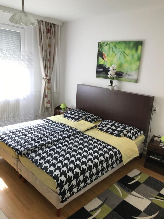 Schlafzimmer mit einem Bett mit einer schwarzen und weißen Bettdecke in der Unterkunft Zen apartman in Szolnok