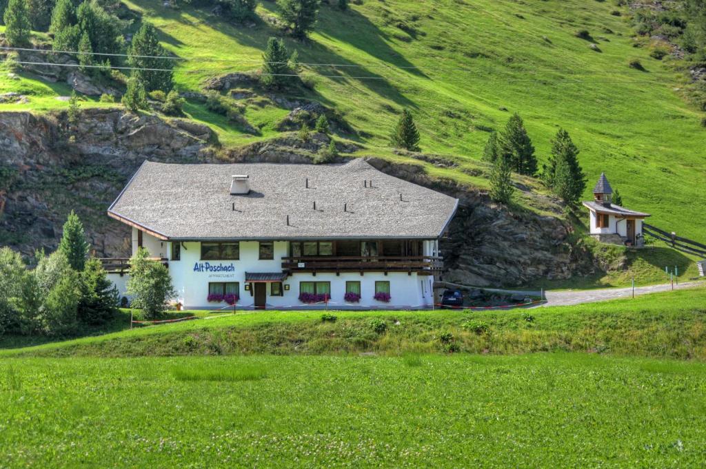 ein großes weißes Haus auf einem Hügel mit grünem Feld in der Unterkunft Alt Poschach in Obergurgl
