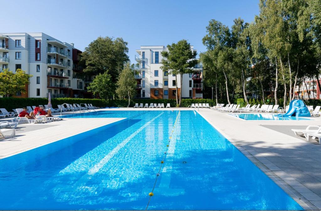 uma grande piscina com cadeiras e água azul em Apartament 203 - Kołobrzeg Polanki - Pool & Beach em Kolobrzeg