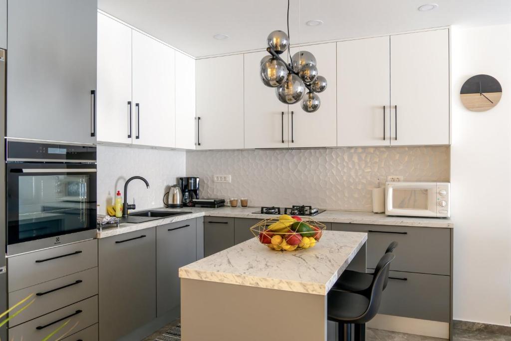a kitchen with white cabinets and a bowl of fruit on a counter at Comfort Apartment Dorin in Makarska