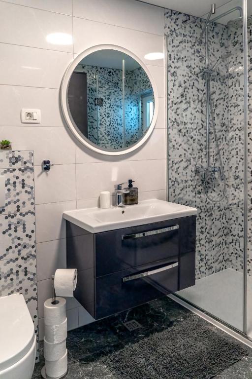 a bathroom with a sink and a mirror and a shower at Comfort Apartment Dorin in Makarska