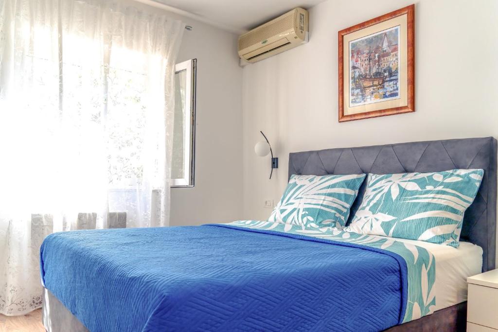 a bedroom with a blue bed and a window at Comfort Apartment Dorin in Makarska