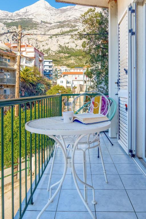 a table on a balcony with a book on it at Comfort Apartment Dorin in Makarska