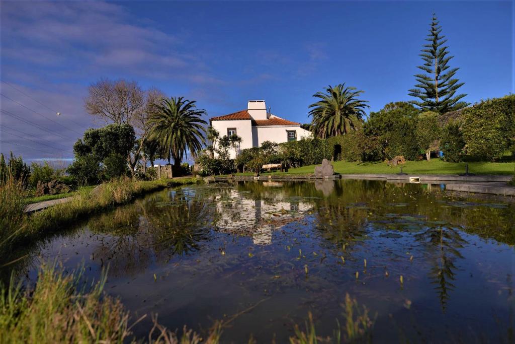 um grande lago em frente a um edifício com palmeiras em Quinta do Bom Despacho em Ponta Delgada