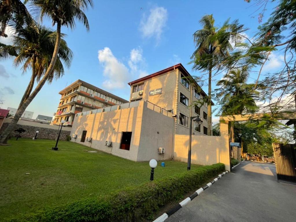 ein Gebäude mit Palmen vor einem Park in der Unterkunft The Chesterfield Hotel in Lagos