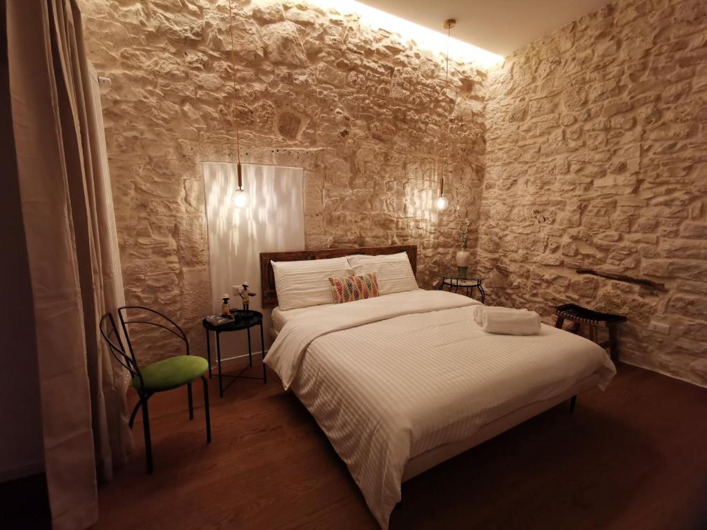 1 dormitorio con cama y pared de piedra en Aracoeli 20, en Cassano delle Murge