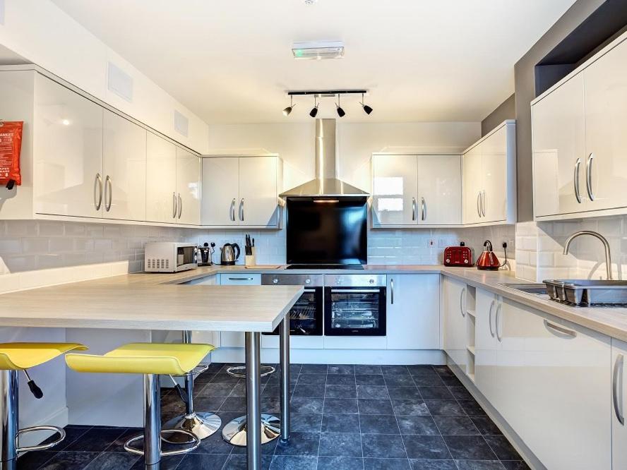 a kitchen with white cabinets and a table and chairs at Townhouse PLUS @ 166 Edleston Road Crewe in Crewe