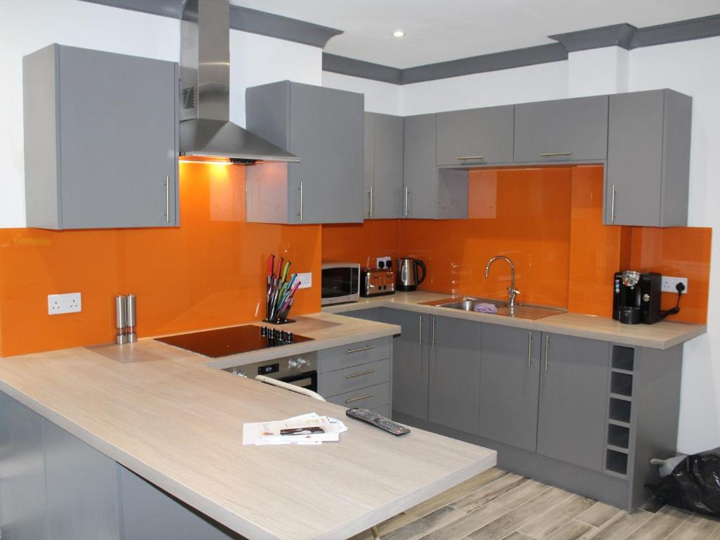 a kitchen with white cabinets and an orange wall at Townhouse PLUS @ 282 Walthall Street in Crewe