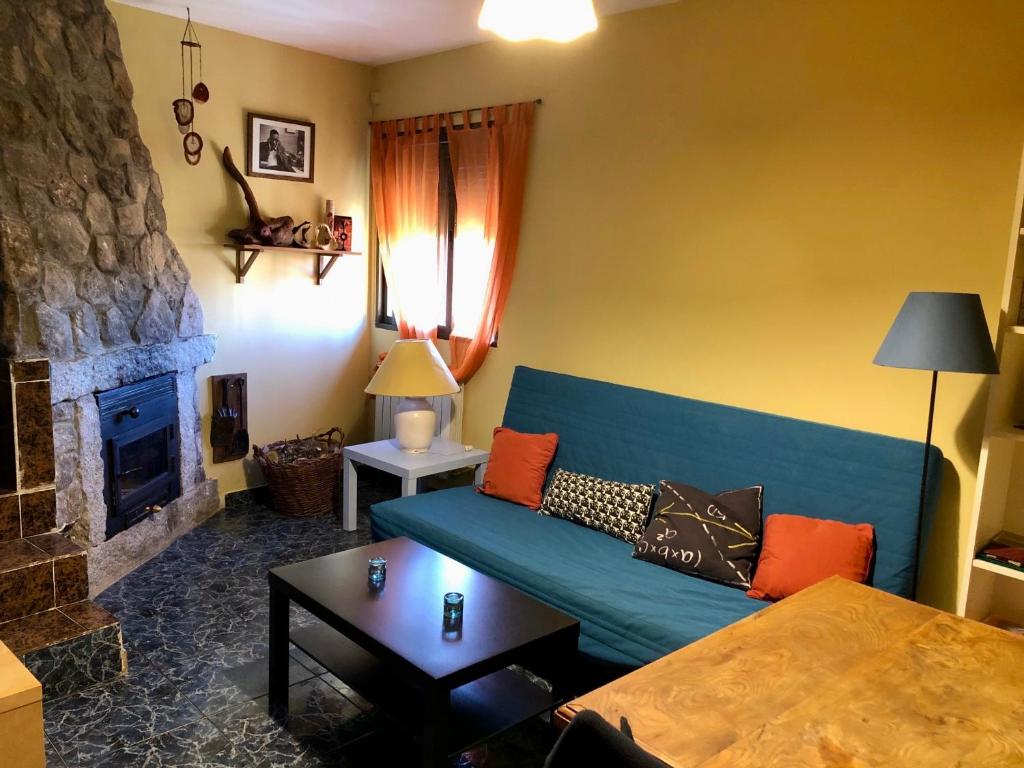 ein Wohnzimmer mit einem blauen Sofa und einem Kamin in der Unterkunft Casa en el corazón de Gredos, amplia y agradable. in Navacepeda de Tormes