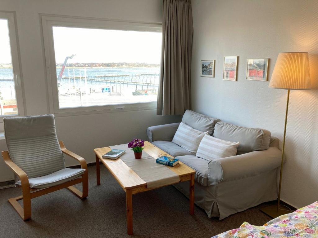 a living room with a couch and a table and a chair at Fehmarn-OstseeferienAm Yachthafen 190 in Burgtiefe auf Fehmarn 