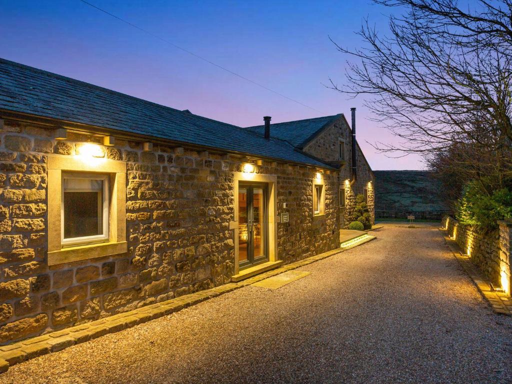 a stone house with lights on the side of it at The Old Shippon Mews in Keighley