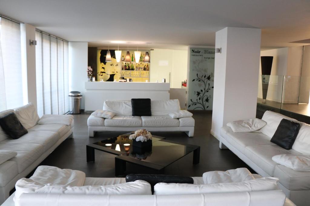 uma sala de estar com sofás brancos e uma mesa de centro em HOTEL QUADRIFOGLIO em Pomigliano dʼArco