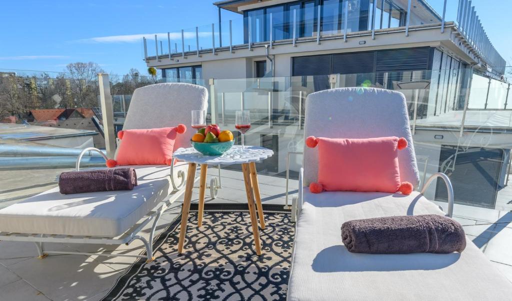 a balcony with two chairs and a table with a bowl of fruit at Lelle Marine Resort Voila Apartman in Balatonlelle