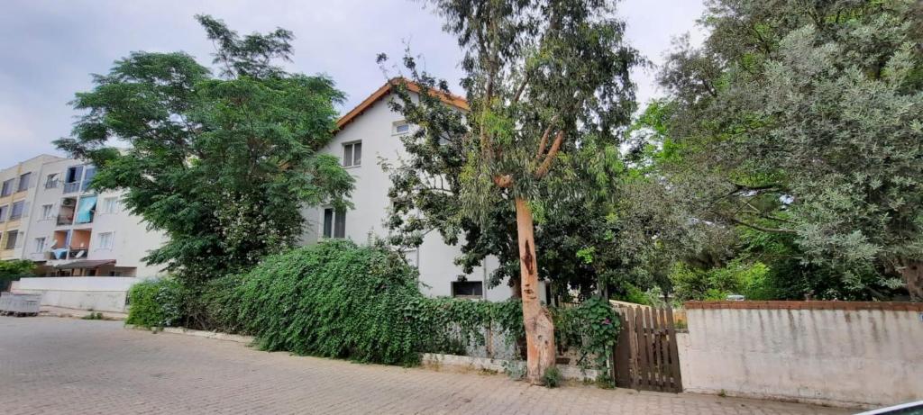 una casa blanca con una valla y árboles en Ecer Pansiyon, en Kusadasi