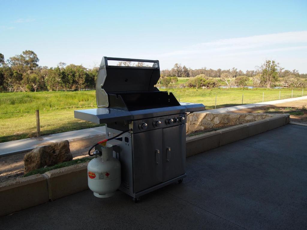a grill sitting on a patio next to a field at Stirling Estate Chalets in Capel