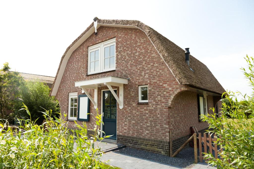 a red brick house with a thatched roof at Het Eerste Huisje vacation home in Noordwijk aan Zee