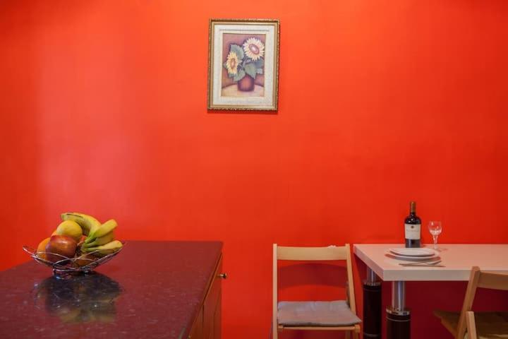 a red wall with a table and a bottle of wine at Pink house in Drepana