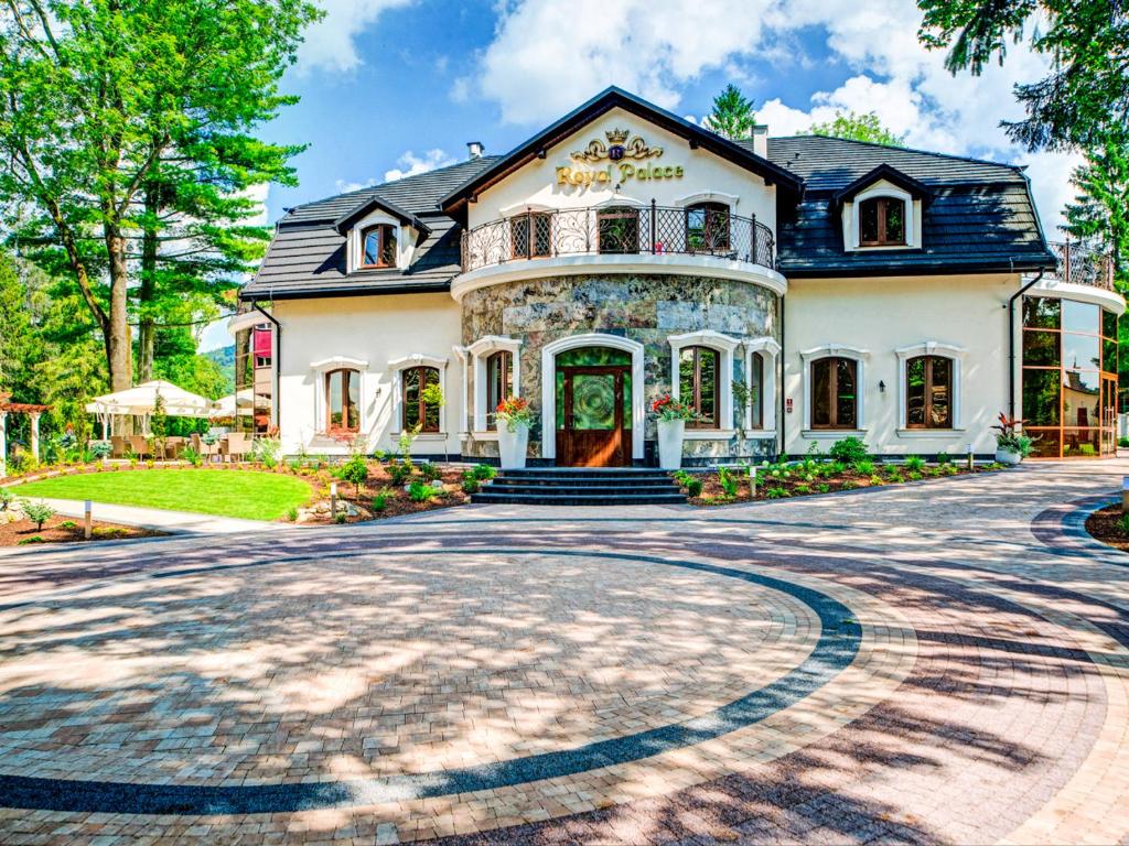 a large white house with a stone driveway at ROYAL PALACE Centrum Bankietowe in Sanok
